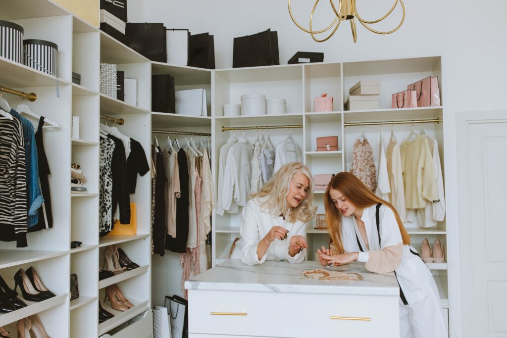 Two people inside their ensuite wardrobe, which is using well organised vertical hanging space.