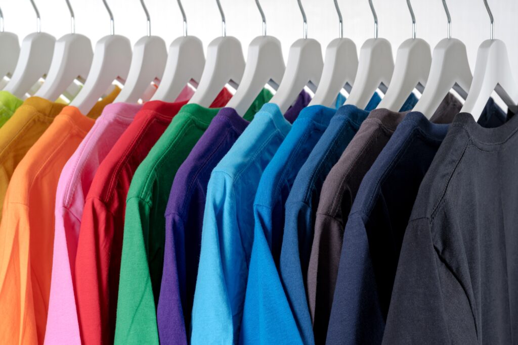 A well organised and tidy collection of t-shirts, hanging on a rail.